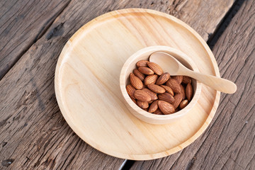 almonds in a wood bowl on grained wood background