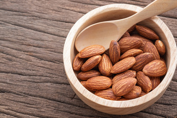 almonds in a wood bowl on grained wood background