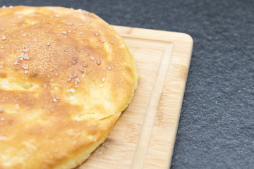 Italian round focaccia with salt on a wooden cutting board. Homemade focaccia with salt and flavorful. Traditional homemade food similar to pizza