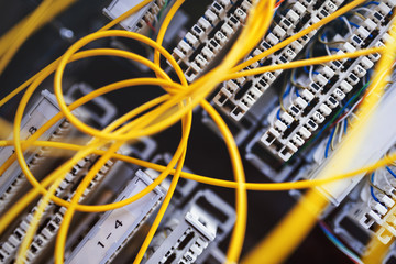 Detail of technological equipment (telephone line) in server room covered with yellow cables.