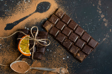 pieces of dark chocolate tied with string and sprinkled with cocoa powder with dried oranges