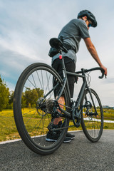 Vertical shot of cyclist with a road bike on the asphalt bicycle path. Close up shot of the rear wheel.