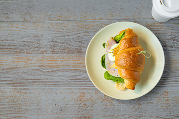ham sandwich with salad, cheese, egg and mustard sauce and coffee to go cup on light wooden background. space for text, top view