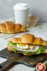 croissant sandwich with green salad, egg, cheese and ham slice. vertical