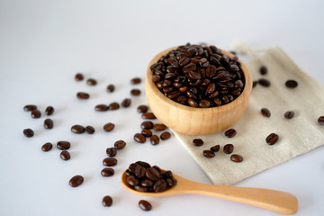 Wooden cup with roasted coffee beans on a white surface The top view with space designed for you.