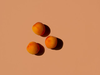 three whole apricots on terracotta background. top view, copy space