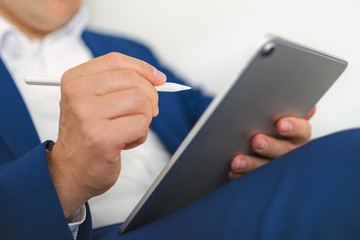 Stylus held in a businessman's hand over a tablet touch screen.