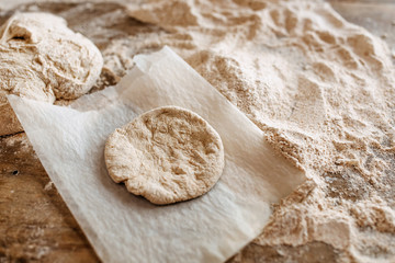 Dough in shape of a griddle-cake on a baking paper on table.