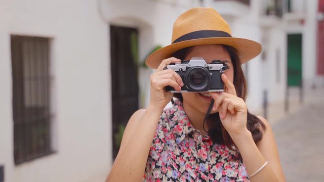 Tourist girl girl  taking a picture with a vintage camera. Beautiful woman with panama hat during summer holiday