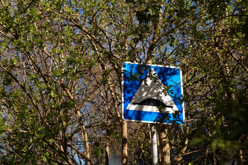 Road sign artificial roughness among the trees on which the leaves bloom