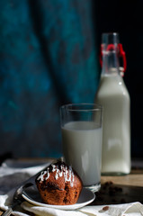chocolate muffins on a table with a glass of milk and flowers