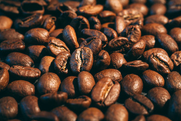 A scattering of coffee beans on a black countertop. The texture of the beans closeup. Vintage style photography..