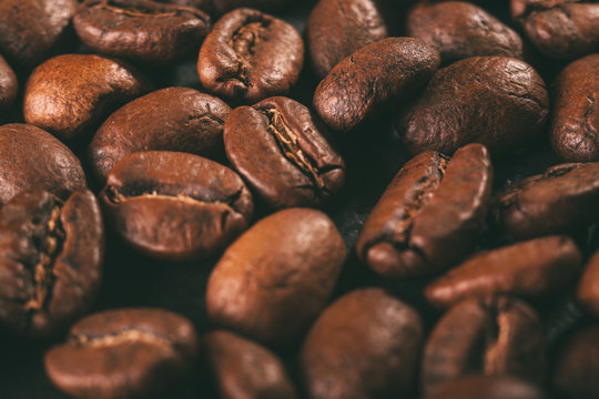 A Scattering Of Coffee Beans On A Black Countertop. The Texture Of The Beans Closeup. Vintage Style Photography..