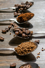 different textures of coffee in spoons on a wooden background, coffee beans, instant coffee, ground coffee