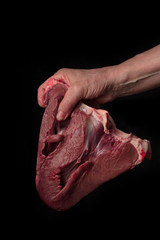 womah hand  holding beef heart on black . close up