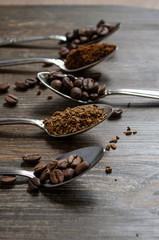 different textures of coffee in spoons on a wooden background, coffee beans, instant coffee, ground coffee