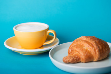 yellow cup with croissant on a blue background