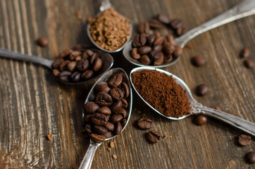 different textures of coffee in spoons on a wooden background, coffee beans, instant coffee, ground coffee