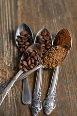 different textures of coffee in spoons on a wooden background, coffee beans, instant coffee, ground coffee