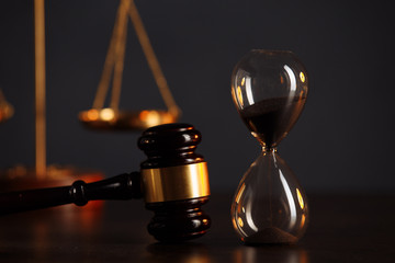 Judge's gavel, scales of justice and hourglass on wooden table. Law concept.