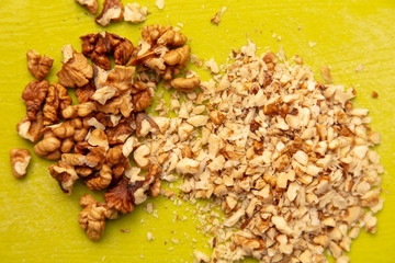 Knife-chopped walnuts on a green plastic board.