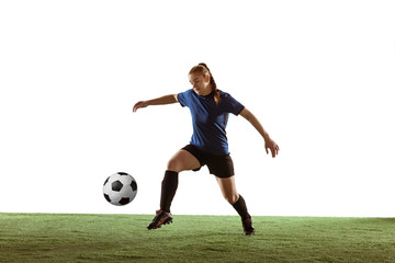 Naklejka premium Young female soccer or football player with long hair in sportwear kicking ball for the goal, training on white studio background. Concept of healthy lifestyle, professional sport, motion, movement.