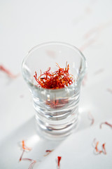 Saffron strand into the crystal glass on the white background