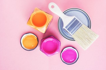 Fototapeta premium Paint cans and new brush on pink background. Focus on brush. House renovation. Color therapy