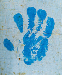 Handprint of blue paint on the wall.