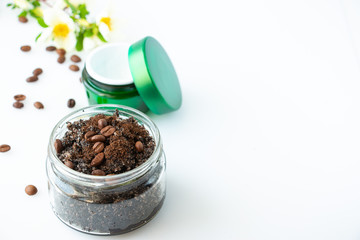 Body scrub made from coffee and sugar in a glass jar and face cream on a white background. The concept of home spa care and beauty. Flat lay.