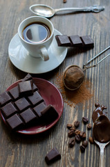 cup of coffee with a piece of chocolate on a wooden background