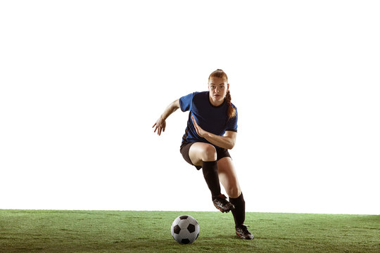Young female soccer or football player with long hair in sportwear kicking ball for the goal, training on white studio background. Concept of healthy lifestyle, professional sport, motion, movement.