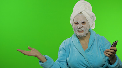 Grandmother in bathrobe, face mask. Woman with smartphone pointing at something