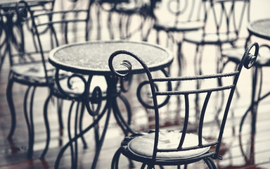Forged furniture on summer terrace of street cafe after rain. Empty summer terrace without people in the evening, crisis of cafes and restaurants, lack of visitors