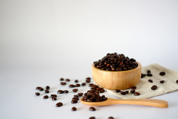 Fototapeta na wymiar Wooden cup with roasted coffee beans on a white surface The top view with space designed for you.