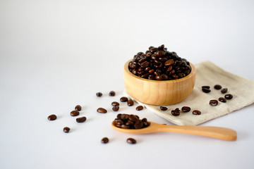 Fototapeta na wymiar Wooden cup with roasted coffee beans on a white surface The top view with space designed for you.