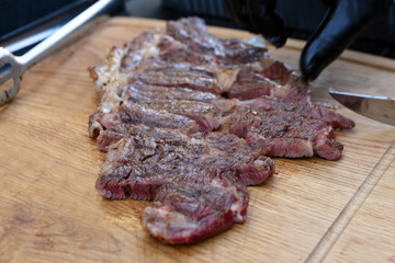 cutting meat with knife on grill fire