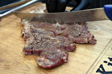 cutting meat with knife on grill fire