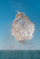 Exploded water, abstract water shape in the air over the sea with blue sky background