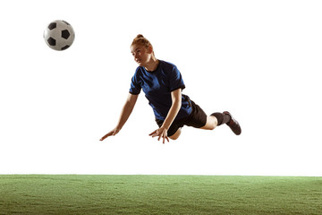 Young female soccer or football player with long hair kicking ball for the goal in flight, jumping high on white studio background. Concept of healthy lifestyle, professional sport, motion, movement.