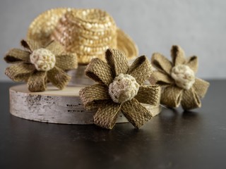 3 burlap flowers and a straw hat sitting on real wood for a rustic country home decor.