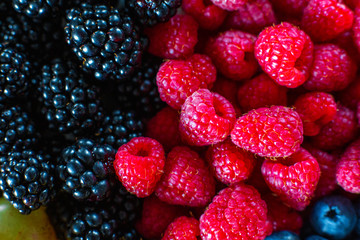 Close-up of raspberry and black mulberry berries split frame. Summer vitamins, sweet berries.