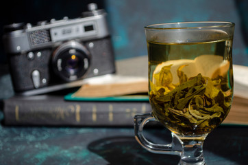 stack of old books on the table with a cup of green tea and a vintage camera