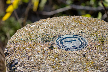 Selective focus on metallic plate on concrete pole to indicate geodesic point. Translation is...