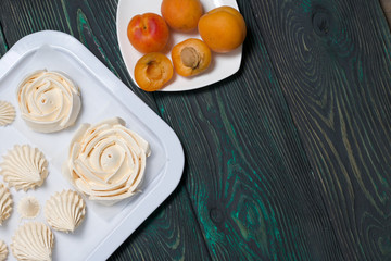 Marshmallows laid out on a tray. Nearby are ripe apricots.