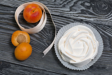 Marshmallows laid out on a tray. Nearby are ripe apricots.