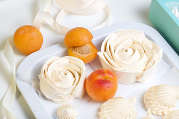 Marshmallows laid out on a tray. Nearby are ripe apricots.