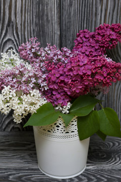 A bouquet of lilacs of different colors. Against the background of painted pine boards.