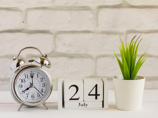 July 24 on a wooden calendar next to the alarm clock.Calendar date, holiday event, or birthday.One...