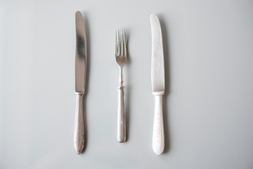 Silverware, old used silver knifes and fork on gray surface, tip view